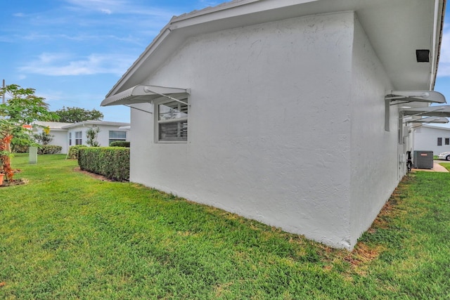 view of side of home with a lawn and central AC