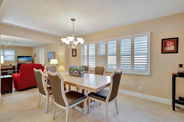 tiled dining room with ceiling fan with notable chandelier, a healthy amount of sunlight, and a textured ceiling