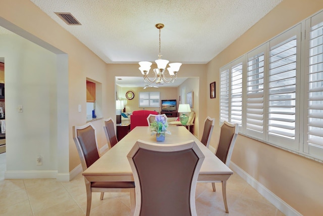 dining area featuring a textured ceiling, a notable chandelier, and light tile patterned flooring