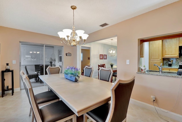 tiled dining room with sink and a notable chandelier