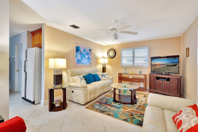 tiled living room with a textured ceiling, ceiling fan, and wooden walls