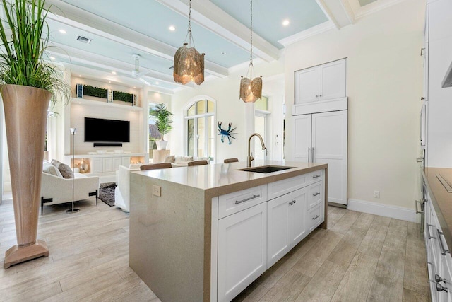 kitchen with white cabinets, light hardwood / wood-style floors, sink, and a kitchen island with sink