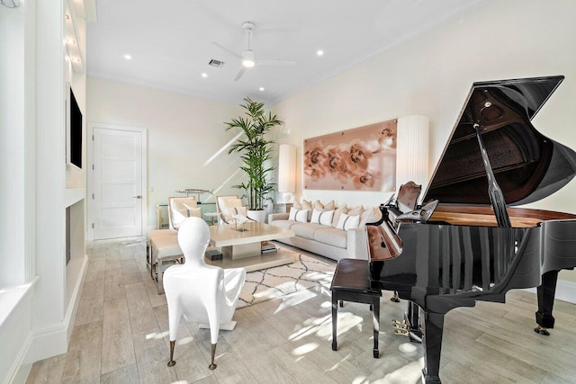 living room with ornamental molding, ceiling fan, and light hardwood / wood-style flooring