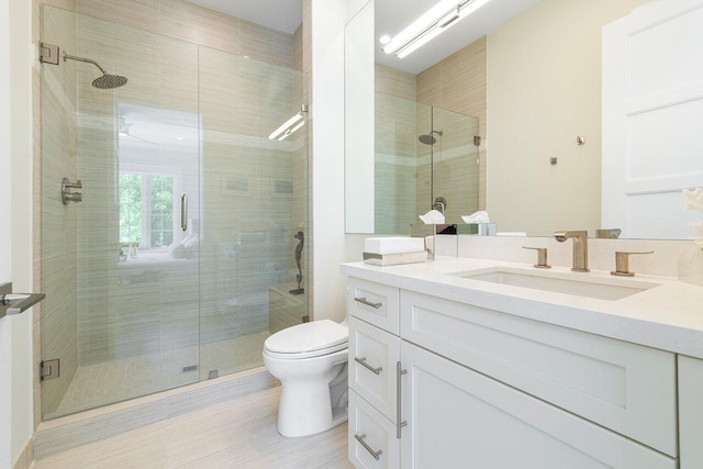 bathroom featuring a shower with door, vanity, and toilet