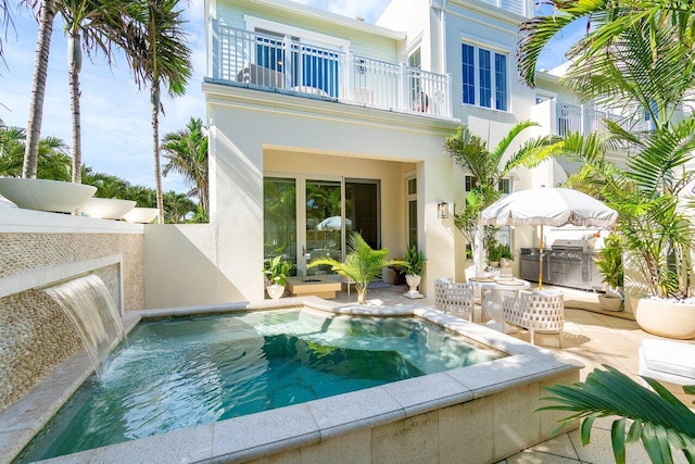 rear view of house featuring a balcony, a patio, a jacuzzi, and pool water feature