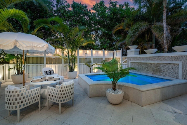 pool at dusk featuring an outdoor fire pit, a jacuzzi, and a patio area