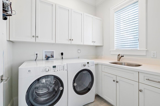 laundry area featuring cabinets, washing machine and dryer, sink, and crown molding