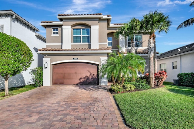 mediterranean / spanish house with central air condition unit, a front yard, and a garage