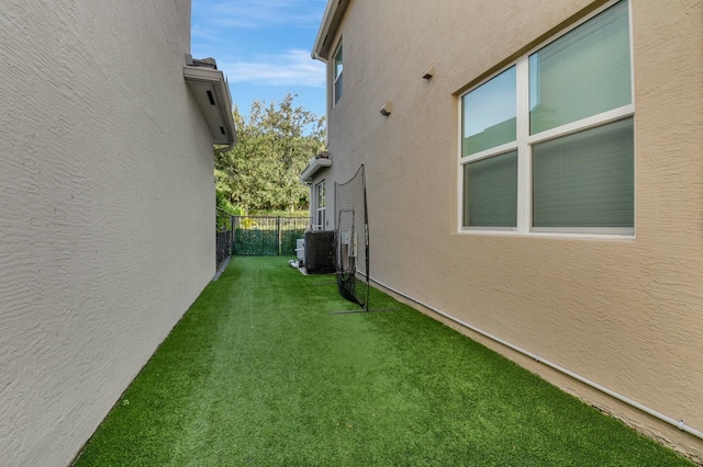 view of side of property with a lawn and central AC