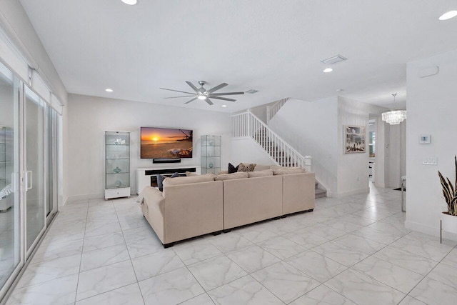 living room with ceiling fan with notable chandelier and a fireplace