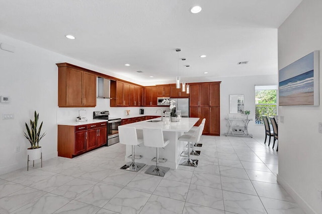 kitchen featuring appliances with stainless steel finishes, a kitchen breakfast bar, sink, wall chimney range hood, and hanging light fixtures