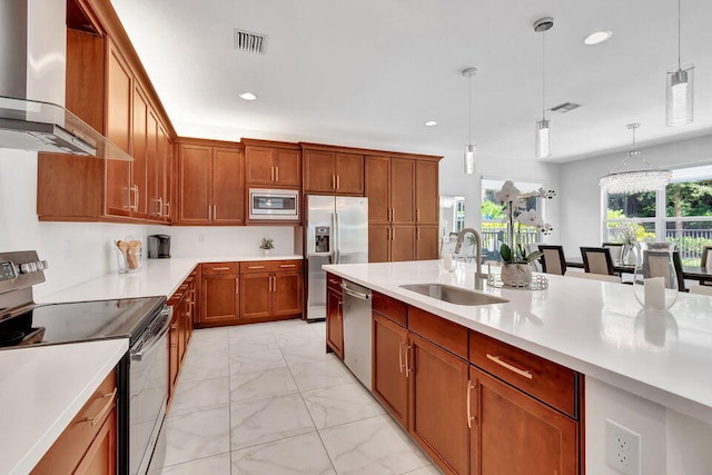 kitchen featuring sink, wall chimney exhaust hood, decorative light fixtures, and appliances with stainless steel finishes