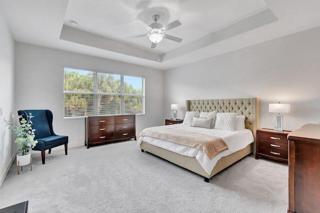 carpeted bedroom featuring ceiling fan and a raised ceiling