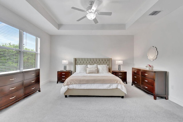 carpeted bedroom featuring a raised ceiling and ceiling fan