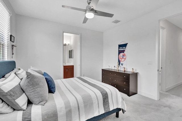 carpeted bedroom with ensuite bath and ceiling fan