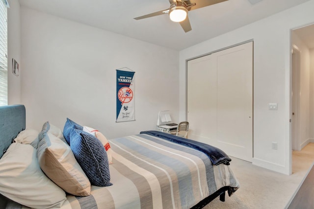 bedroom featuring multiple windows, a closet, light colored carpet, and ceiling fan