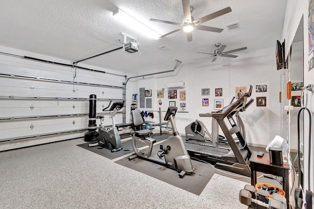 workout area featuring a wall mounted AC, ceiling fan, and a textured ceiling