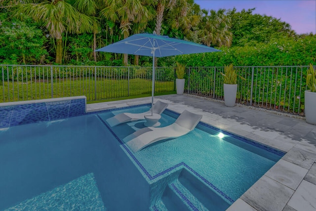 pool at dusk with a yard and pool water feature