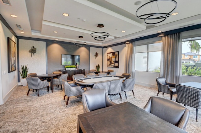 dining area featuring a notable chandelier, a raised ceiling, and light colored carpet