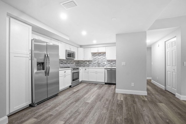 kitchen featuring light hardwood / wood-style floors, white cabinets, sink, tasteful backsplash, and appliances with stainless steel finishes