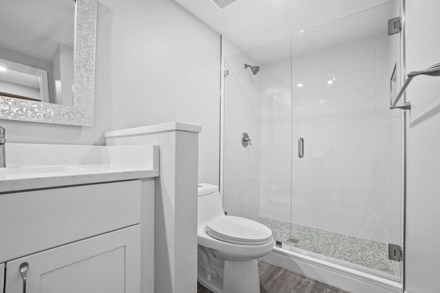 bathroom featuring toilet, vanity, hardwood / wood-style flooring, and a shower with shower door