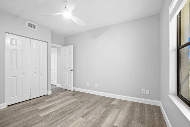 unfurnished bedroom featuring ceiling fan, a closet, and light wood-type flooring