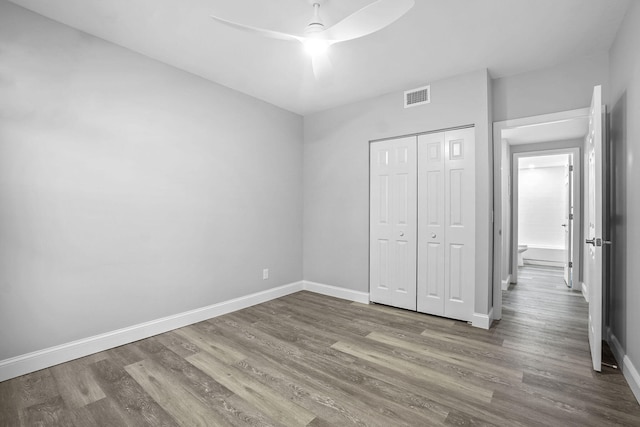 unfurnished bedroom featuring hardwood / wood-style floors, ceiling fan, and a closet