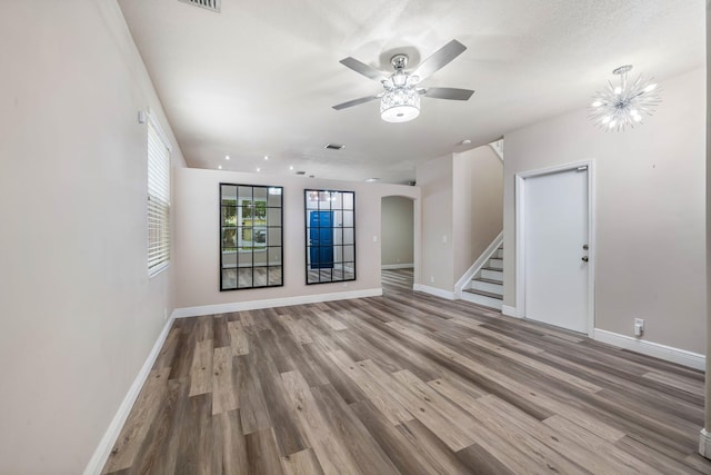 spare room with a textured ceiling, ceiling fan with notable chandelier, and hardwood / wood-style flooring