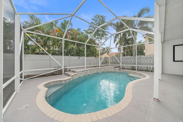 view of pool with glass enclosure and a patio