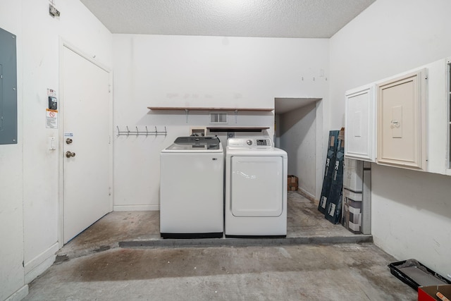 washroom featuring electric panel, a textured ceiling, and washer and clothes dryer