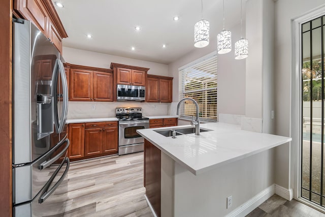 kitchen with kitchen peninsula, sink, backsplash, appliances with stainless steel finishes, and decorative light fixtures