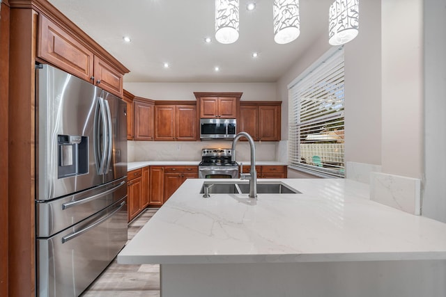 kitchen featuring sink, pendant lighting, appliances with stainless steel finishes, and light hardwood / wood-style flooring