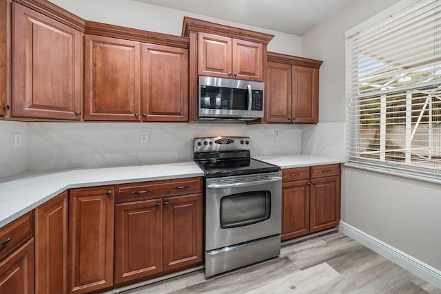 kitchen featuring decorative backsplash, light wood-type flooring, and appliances with stainless steel finishes