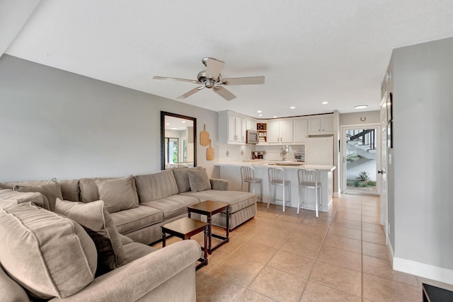 tiled living room featuring a textured ceiling, ceiling fan, and sink