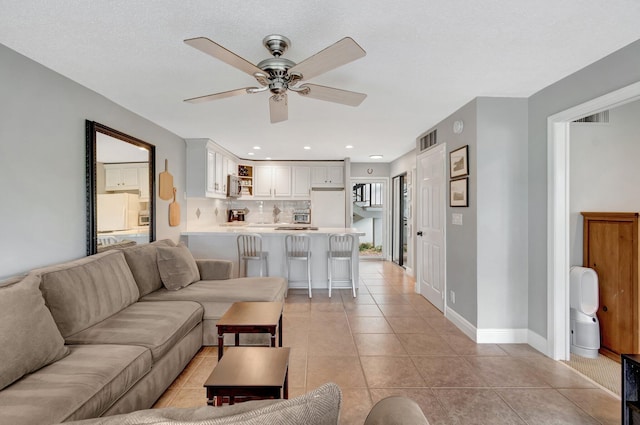 tiled living room featuring a textured ceiling and ceiling fan