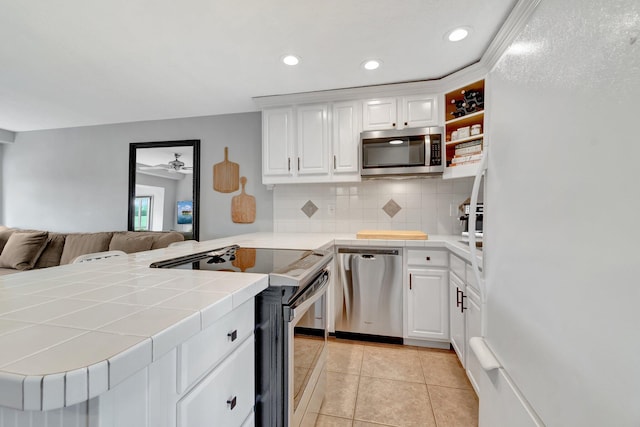 kitchen with kitchen peninsula, white cabinetry, tile counters, and stainless steel appliances