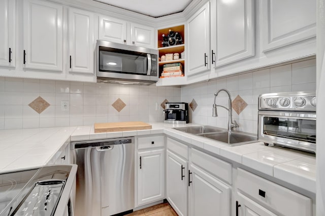 kitchen featuring white cabinets, stainless steel appliances, tile counters, and sink