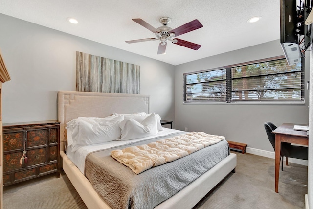 bedroom featuring ceiling fan, light colored carpet, and a textured ceiling