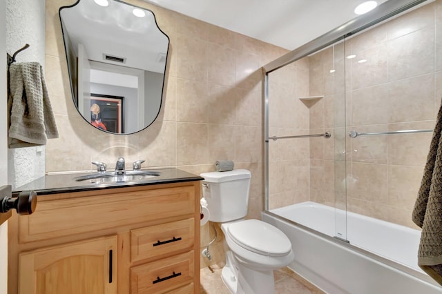 full bathroom featuring vanity, toilet, enclosed tub / shower combo, and tile walls