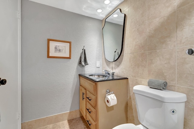 bathroom featuring tile patterned flooring, vanity, tile walls, and toilet