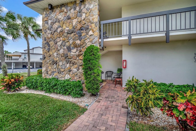 view of exterior entry featuring a balcony and a patio