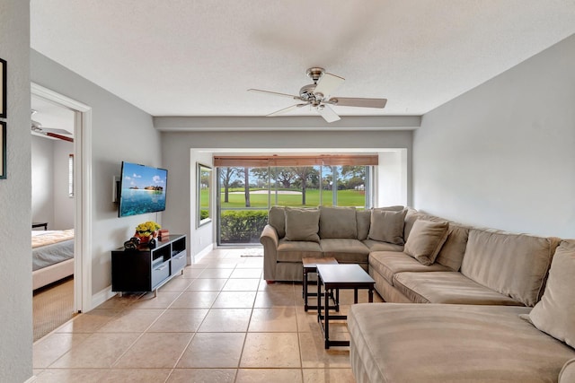 living room with ceiling fan, light tile patterned floors, and a textured ceiling