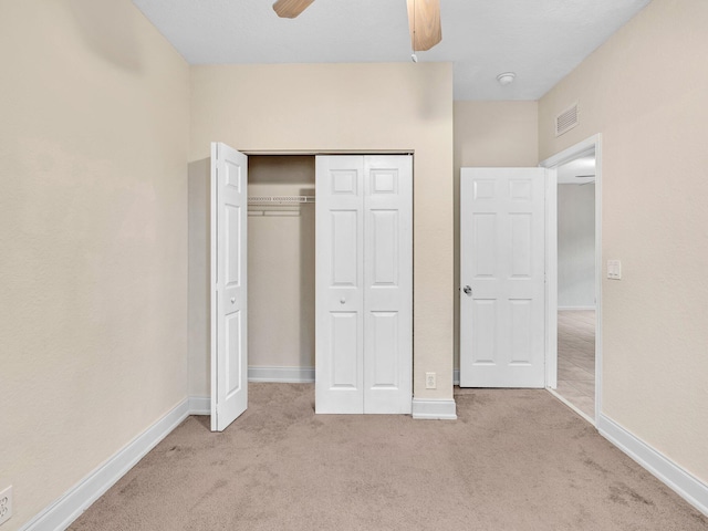 unfurnished bedroom featuring a closet, light colored carpet, and ceiling fan