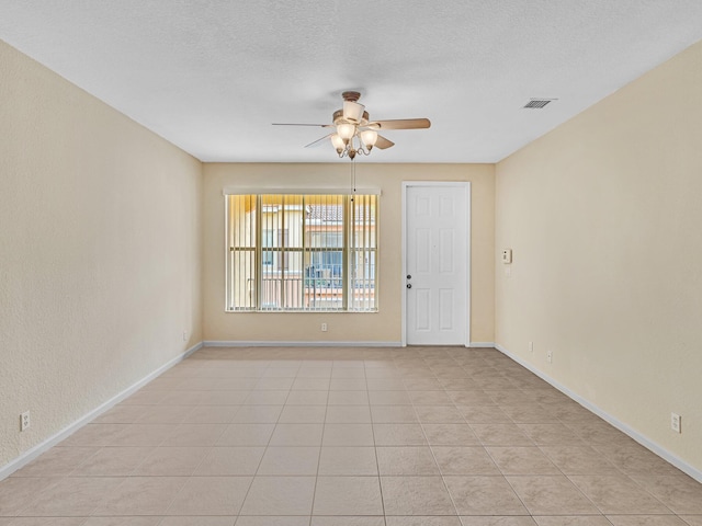 tiled empty room with ceiling fan and a textured ceiling