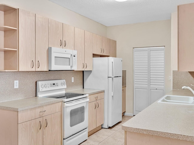 kitchen with sink, light brown cabinetry, a textured ceiling, light tile patterned floors, and white appliances