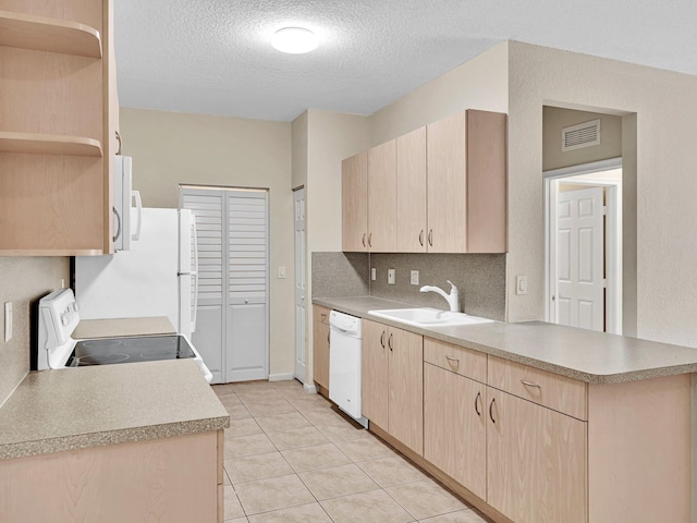 kitchen with sink, kitchen peninsula, light brown cabinetry, a textured ceiling, and white appliances