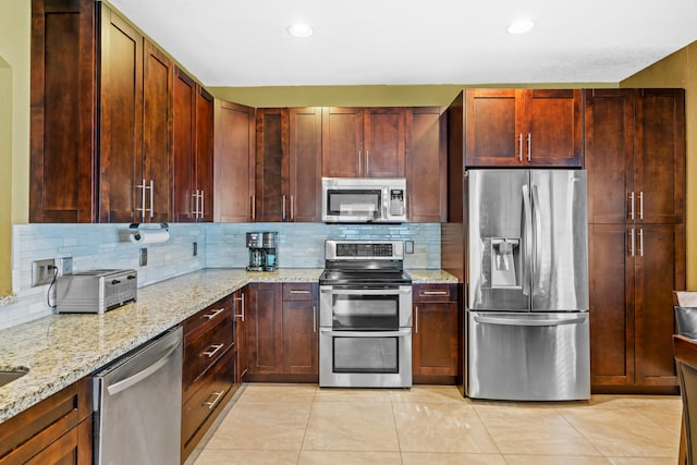 kitchen with backsplash, light stone counters, light tile patterned floors, and stainless steel appliances