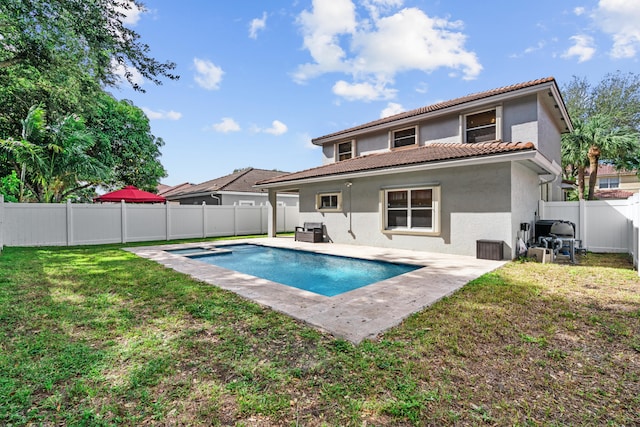 rear view of house with a yard, a fenced in pool, and a patio area