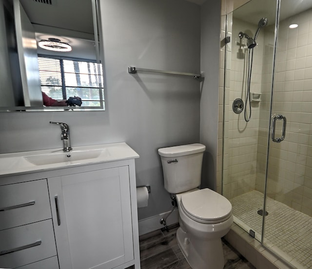 bathroom with toilet, vanity, hardwood / wood-style flooring, and a shower with shower door