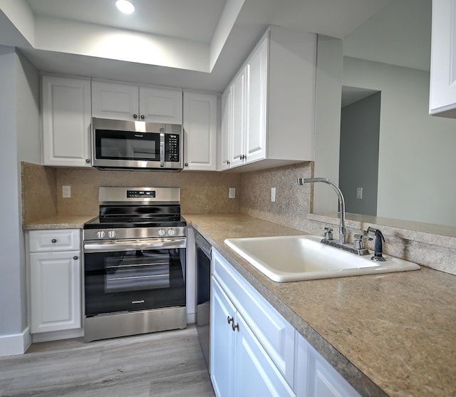 kitchen with white cabinetry, light hardwood / wood-style floors, appliances with stainless steel finishes, and sink